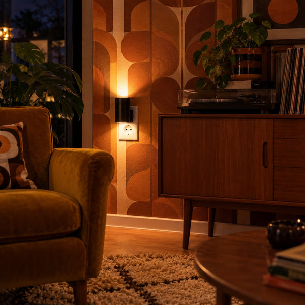 Svart LED-vägglampa tänd i ett retrovardagsrum